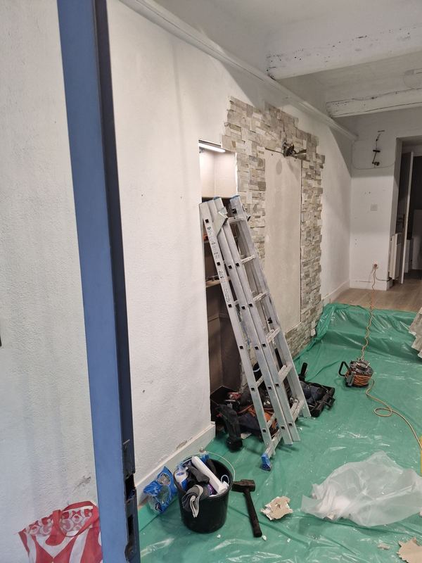 Pendant : mur avec niche et pierre de parement, échelle, outils et sol bâché