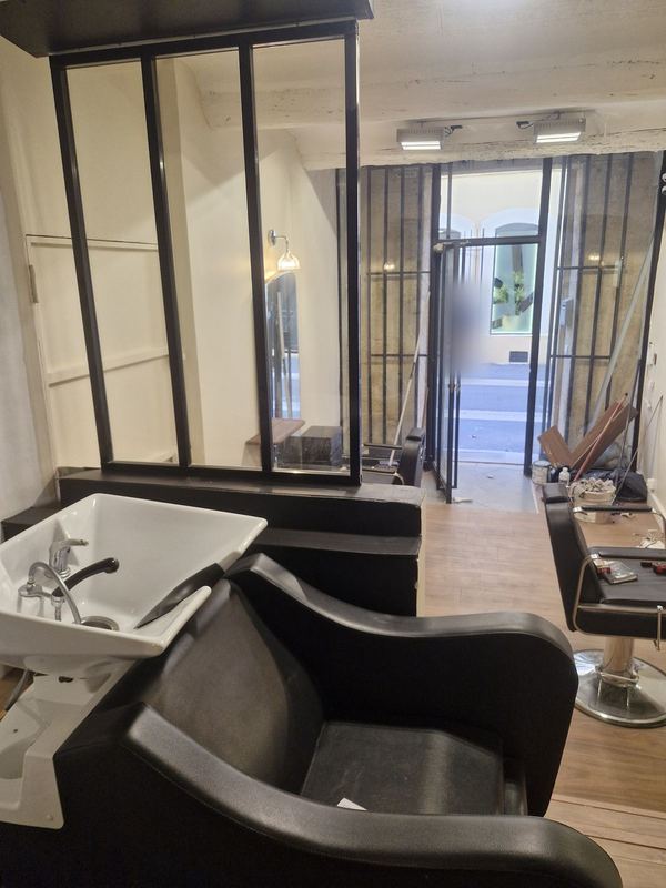 Salon de coiffure terminé : bac à shampoing, fauteuils, verrière et sol effet bois