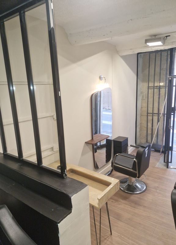 Salon de coiffure terminé : murs clairs, miroir, fauteuil et sol effet bois