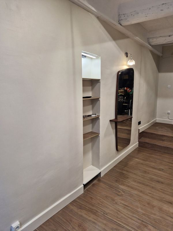 Mur terminé : murs clairs, niche à étagères éclairée, miroir avec tablette et sol effet bois